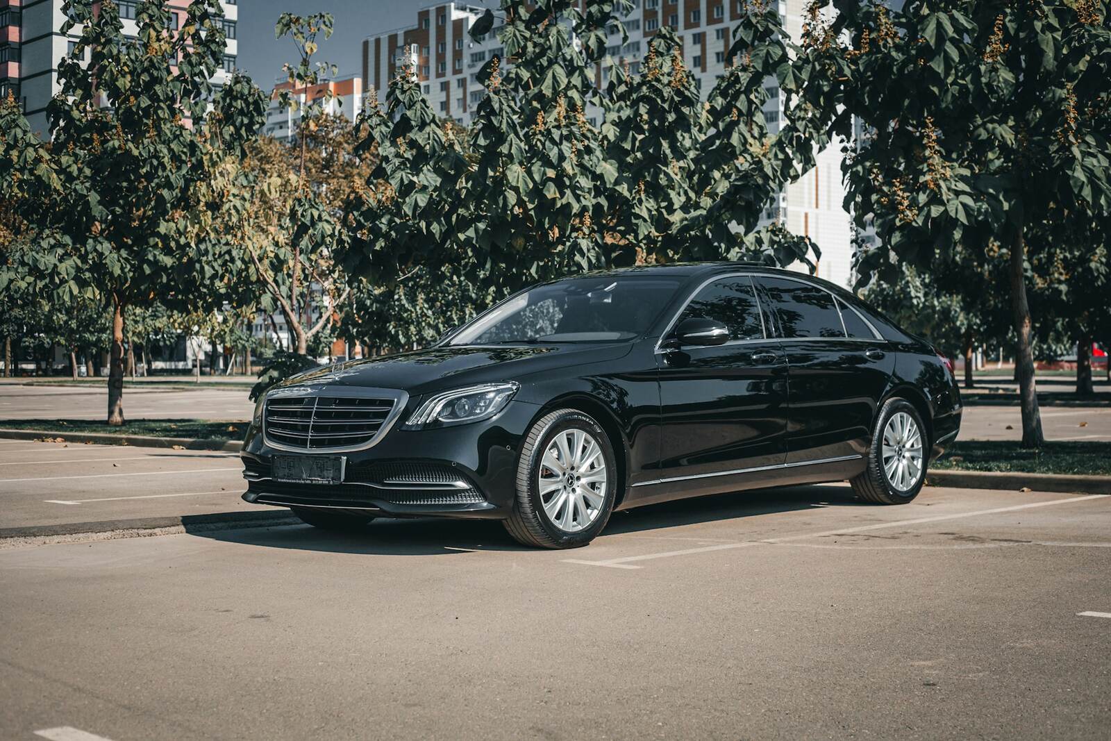 Black premium sedan parked on a tree-lined city street