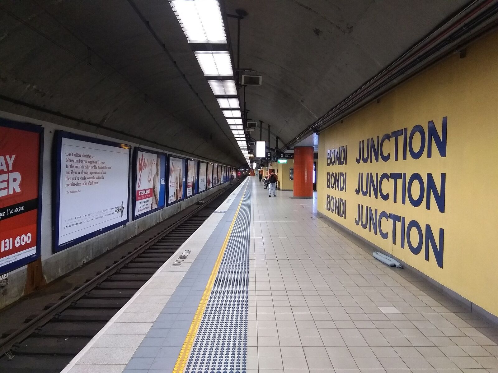 Underground platform at Bondi Junction station with the station name painted in large letters on a yellow wall