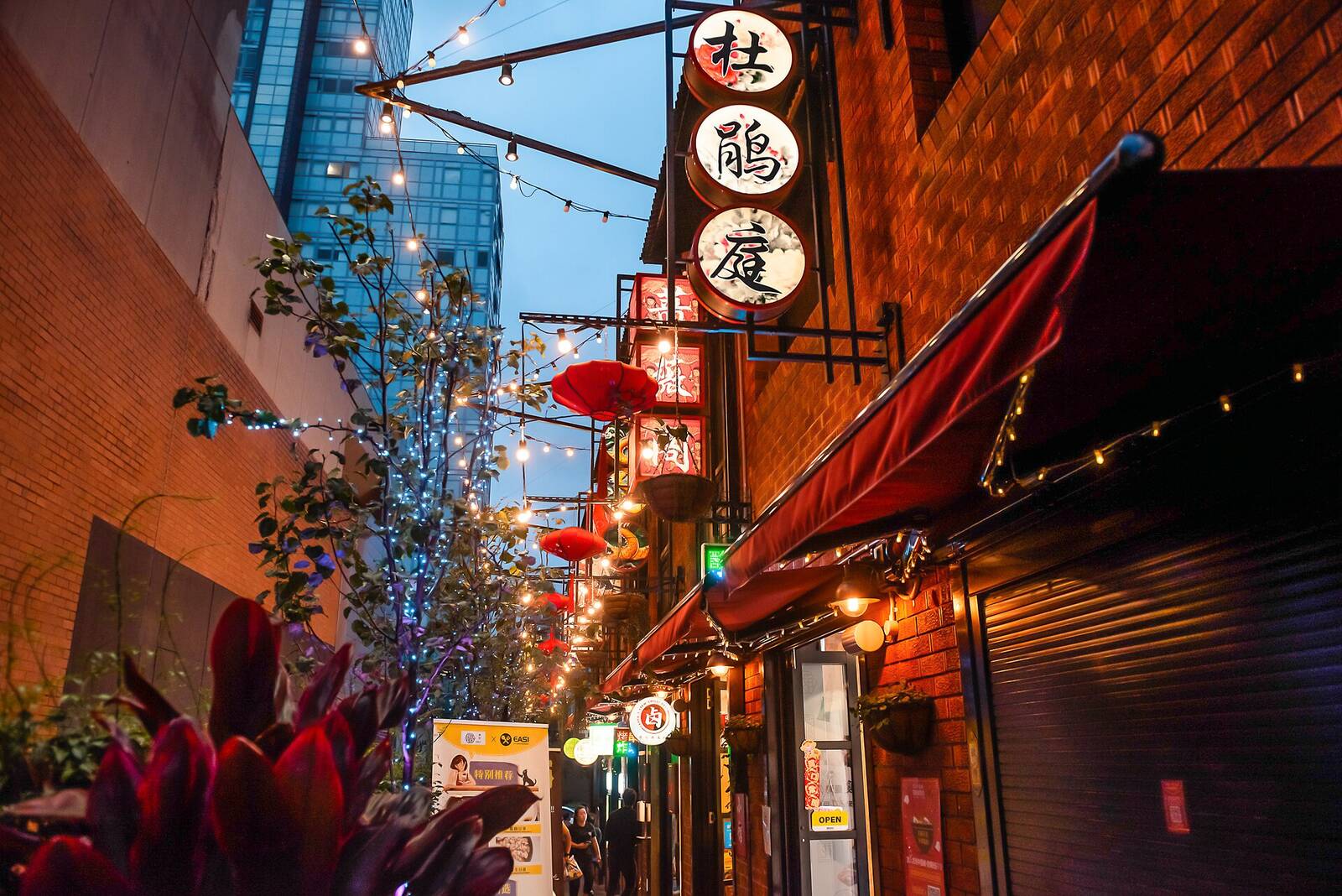 Red lanterns, string lights and restaurant signs in the Clarendon Place laneway at Burwood Chinatown at dusk