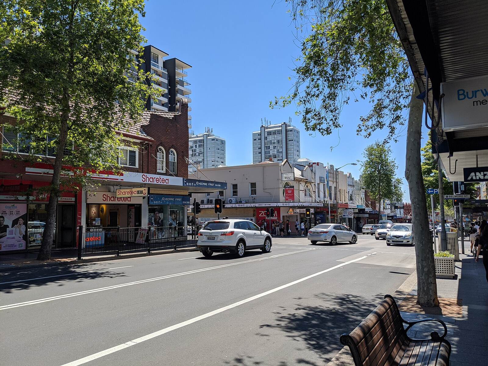 Shops, street trees and traffic on Burwood Road on a sunny day