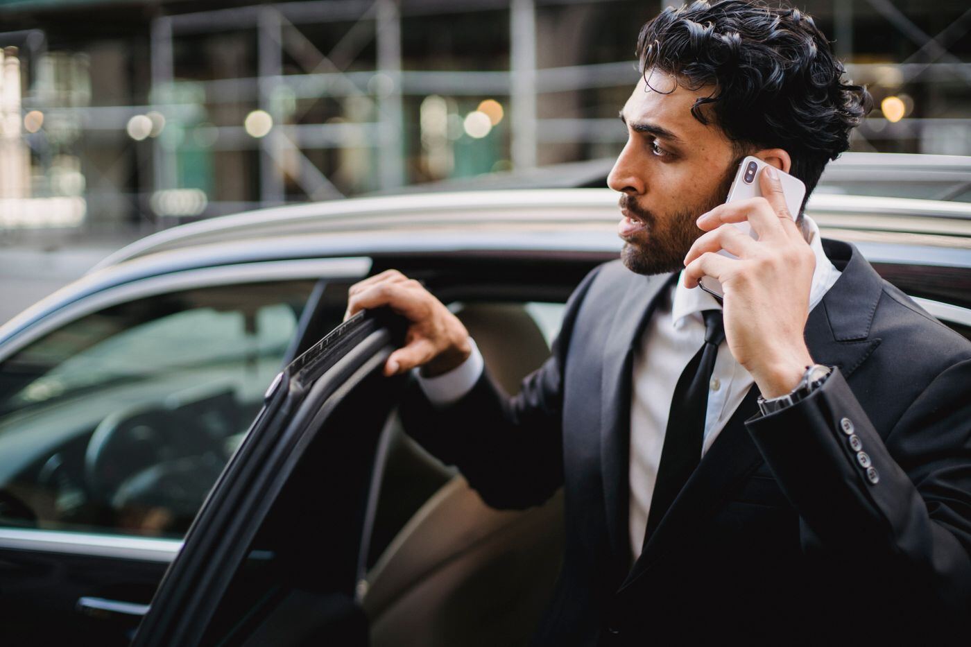 Businessman on a phone call stepping out of a car