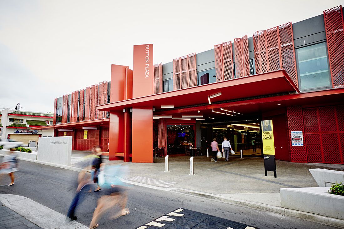 Red slatted facade and entrance of Dutton Plaza in Cabramatta, with shoppers walking past