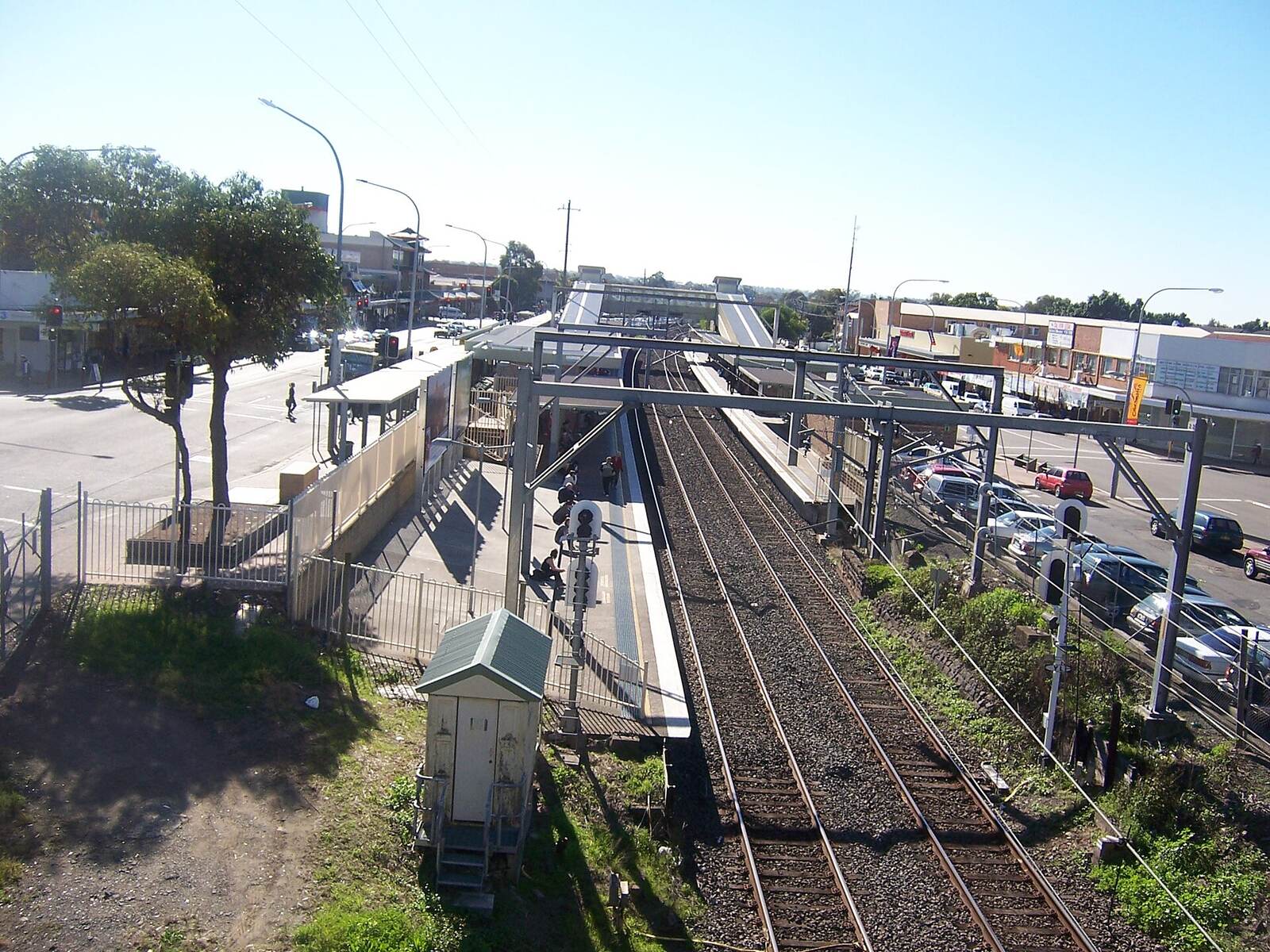 Cabramatta railway station seen from the road overbridge, with the platform, tracks and shops along Railway Parade