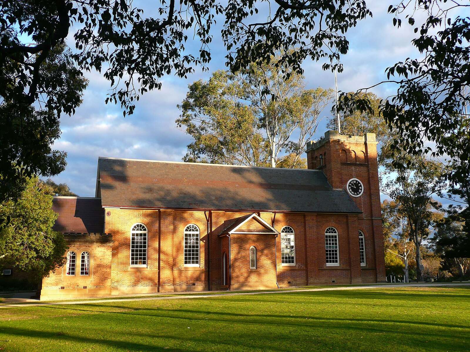 St Peter's Anglican Church in Campbelltown, a brick church with a clock tower, lit by late afternoon sun