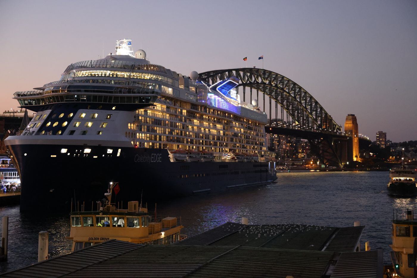 Cruise ship lit up at dusk on Sydney Harbour near the Harbour Bridge
