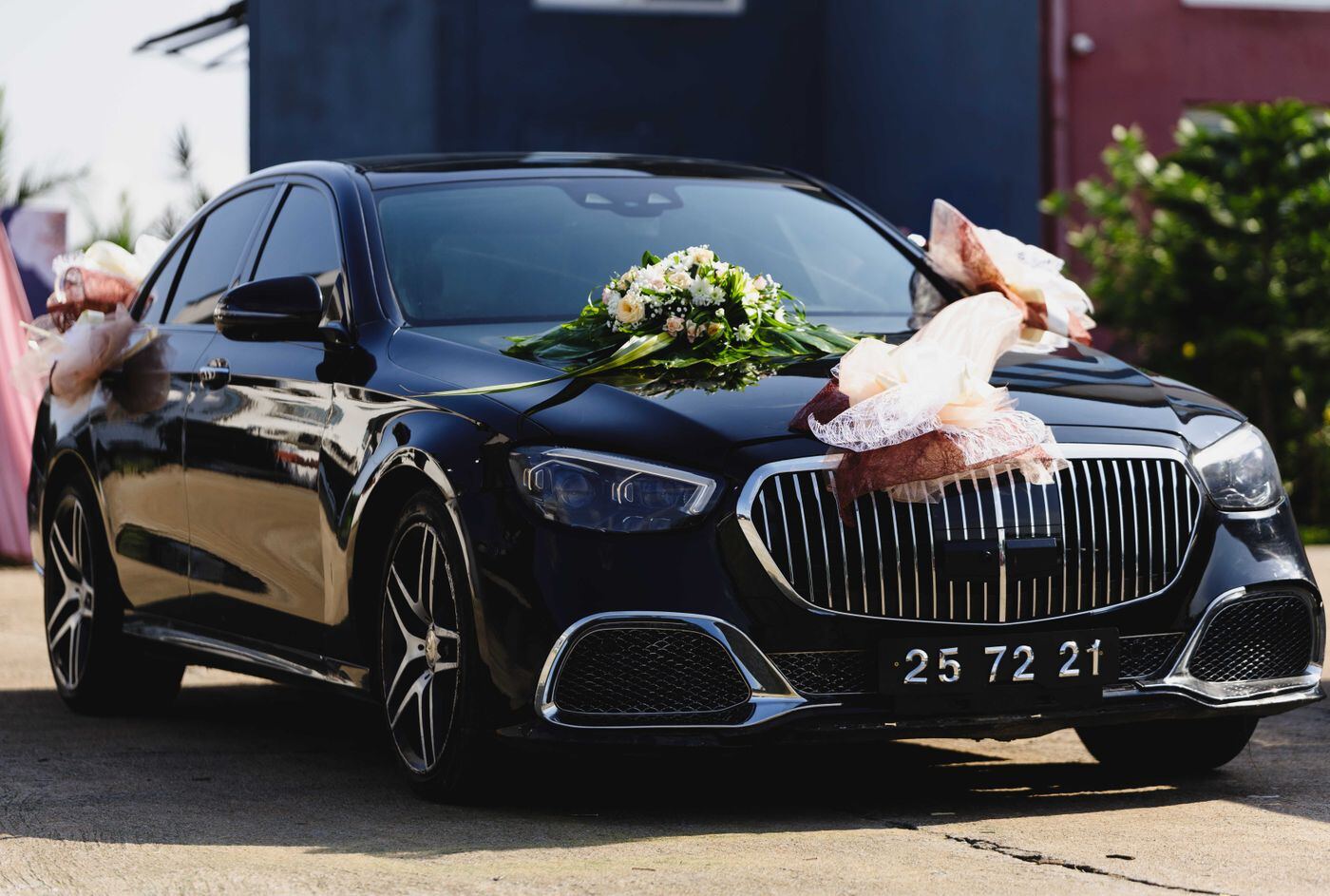 Black wedding car decorated with white ribbon and flowers on the door handle