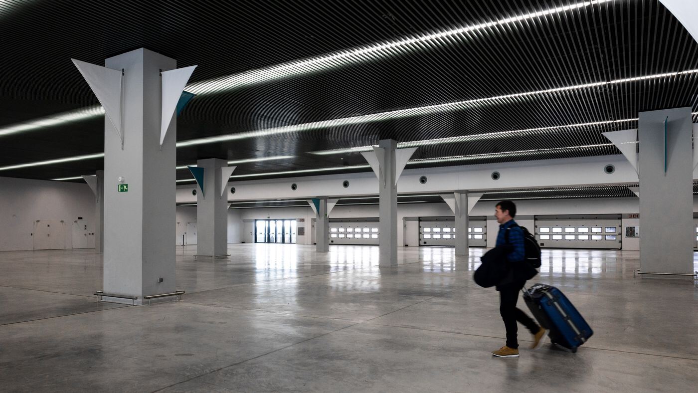 Traveller wheeling a suitcase through a quiet airport arrivals hall early in the morning