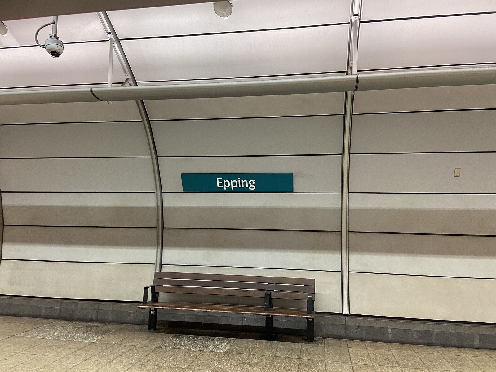 Bench and green Epping name sign on the curved wall of the underground Metro platform