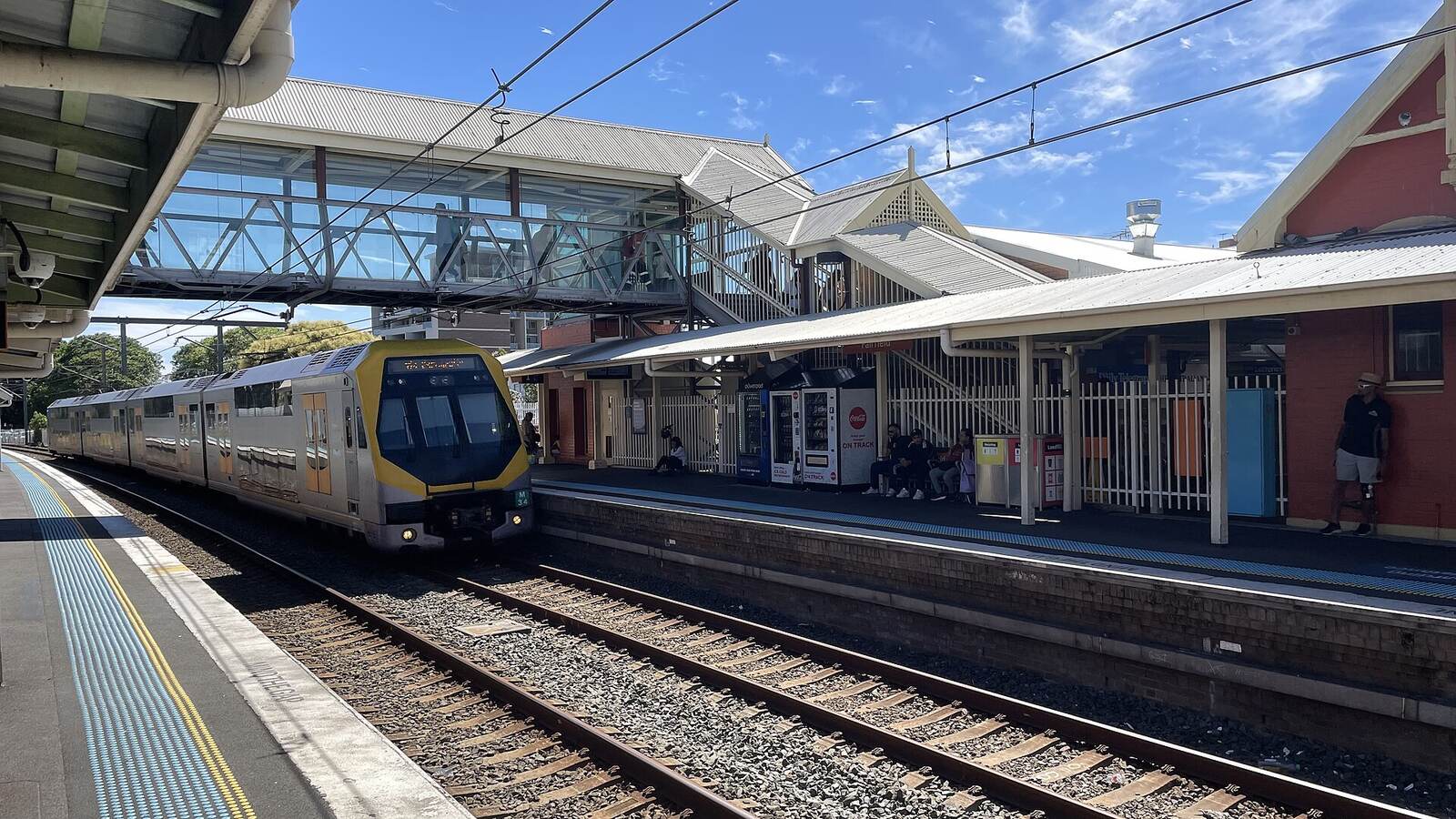 Double-deck Sydney train pulling into Fairfield station beside the heritage platform building and footbridge