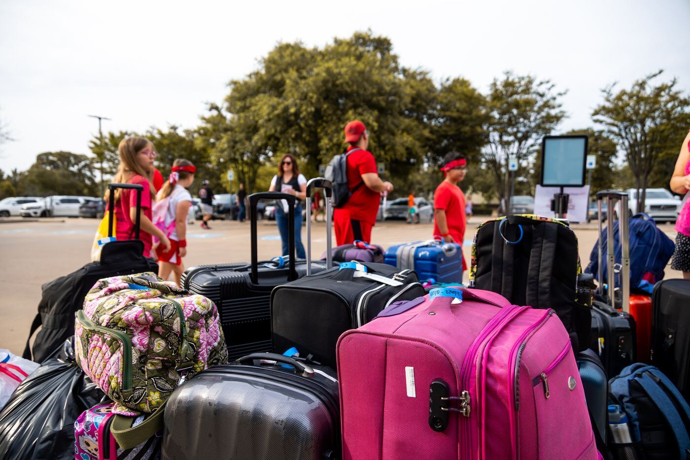 A group of travellers gathered around a large pile of suitcases and bags