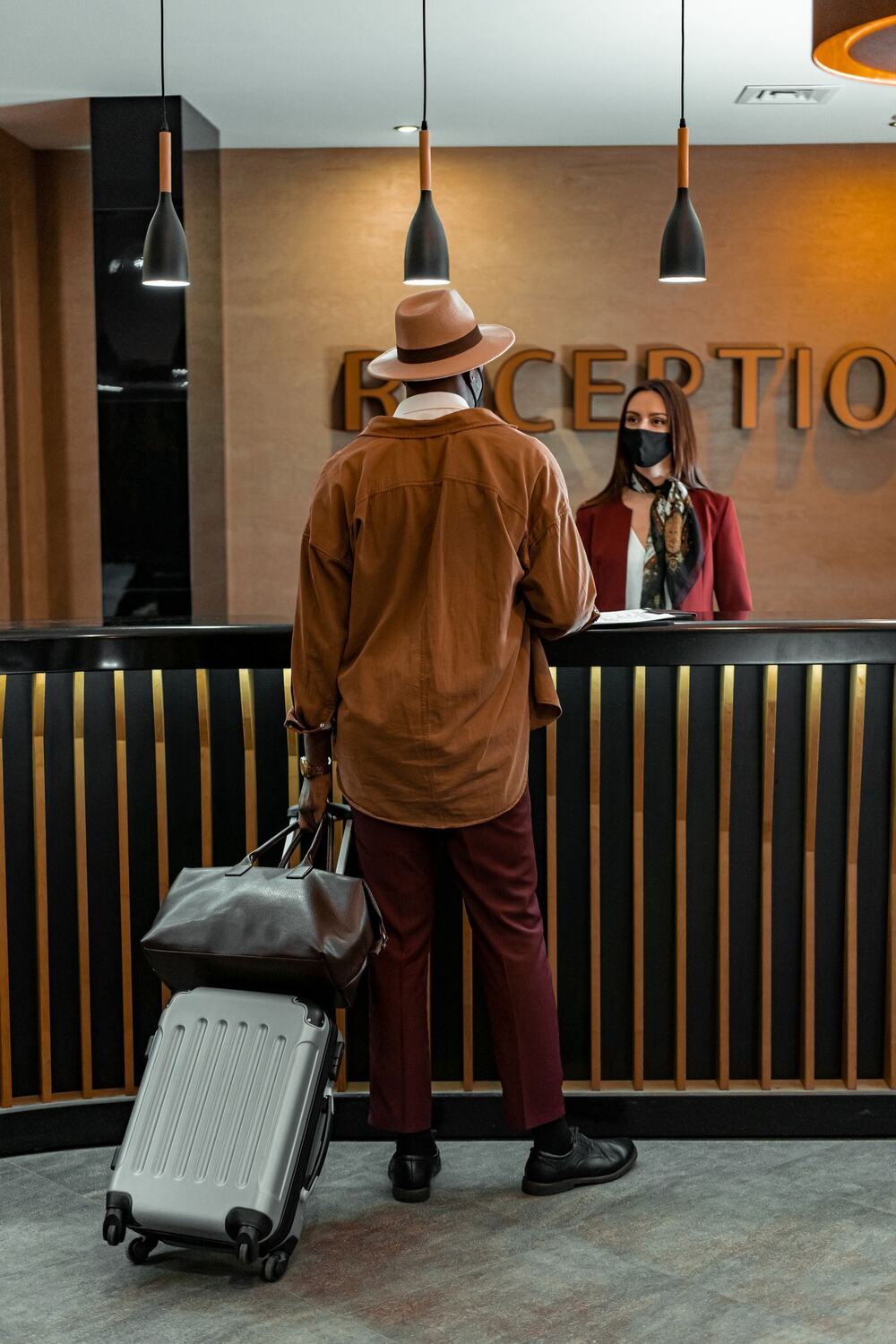 Guest with a suitcase and holdall checking in at a hotel reception desk
