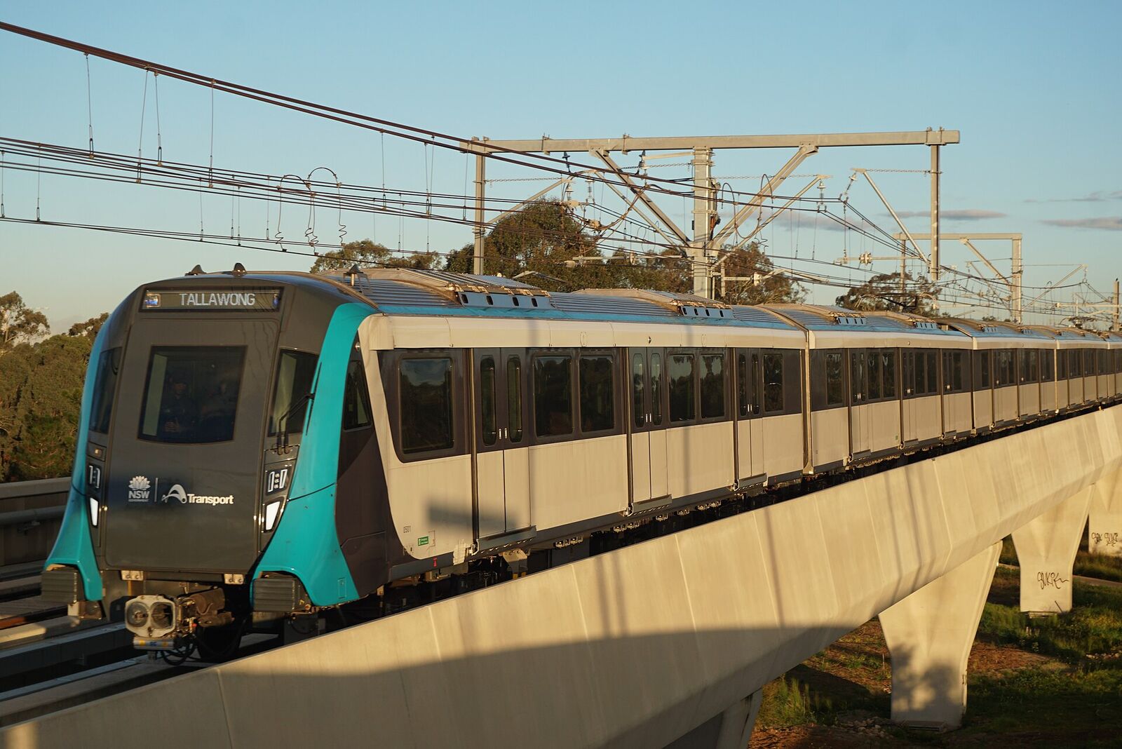 Sydney Metro train bound for Tallawong crossing the concrete viaduct at Kellyville in late afternoon sun