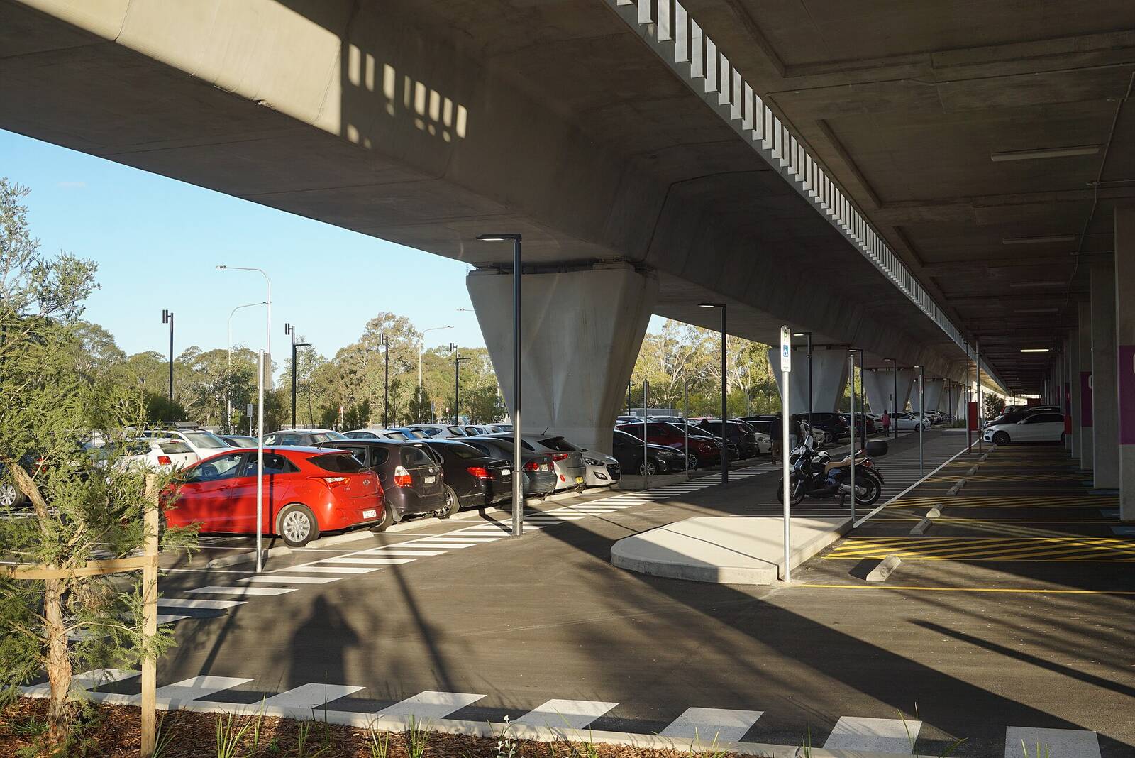 Rows of parked cars in the Kellyville station commuter car park beneath the Metro viaduct