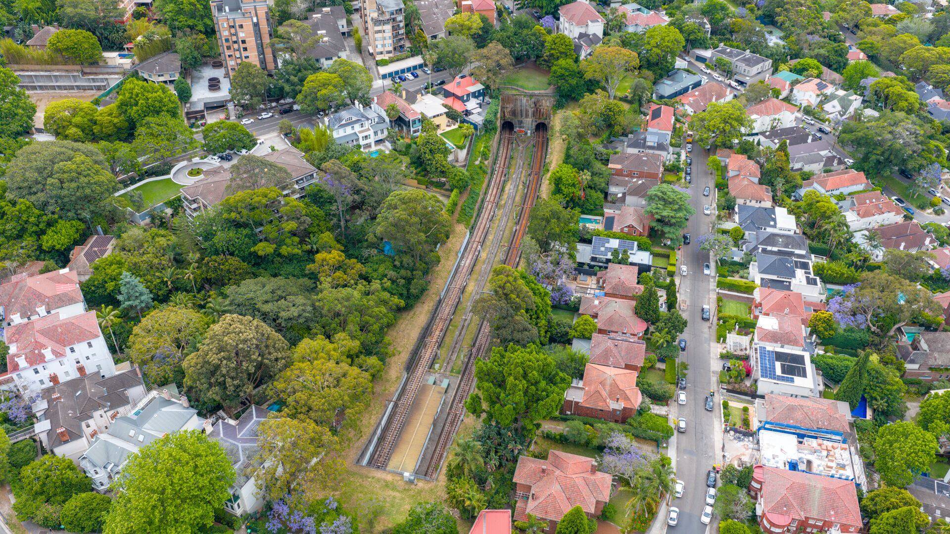 Aerial view of leafy streets and a railway line running into a tunnel on the North Shore