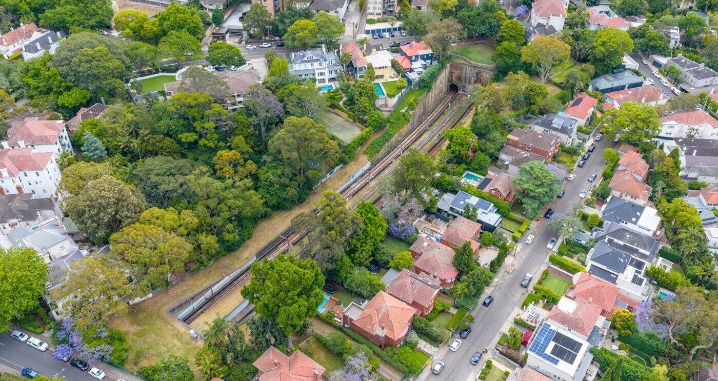 Aerial view of a leafy Sydney suburb with houses, tree-lined streets and a railway cutting