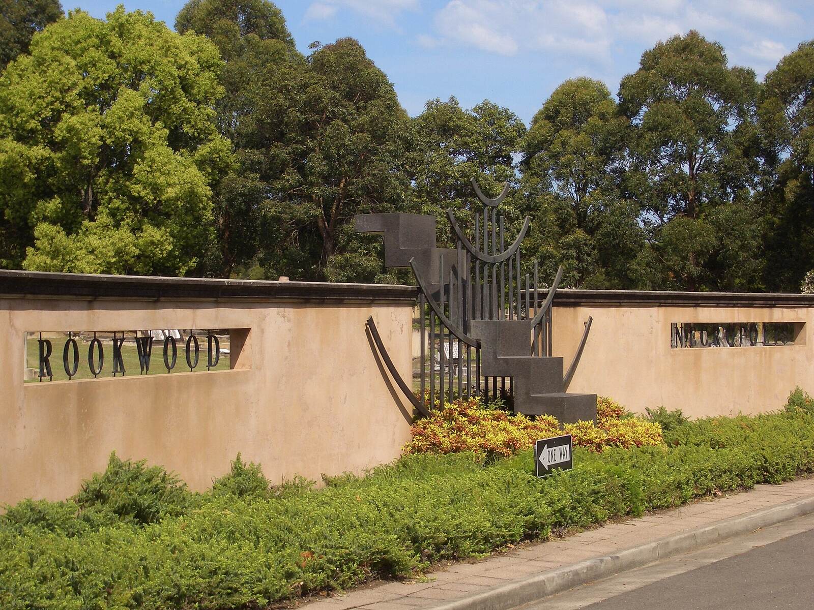 Rookwood name on a rendered entrance wall with gardens and tall trees behind