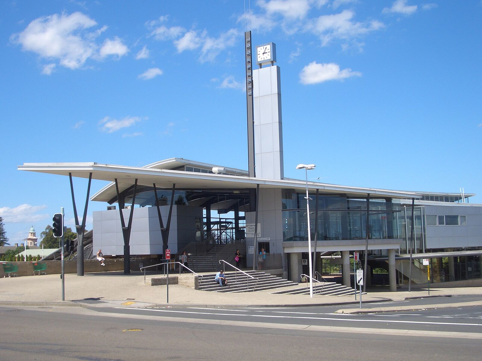 Liverpool railway station entrance with its angled canopy and tall clock tower under a blue sky