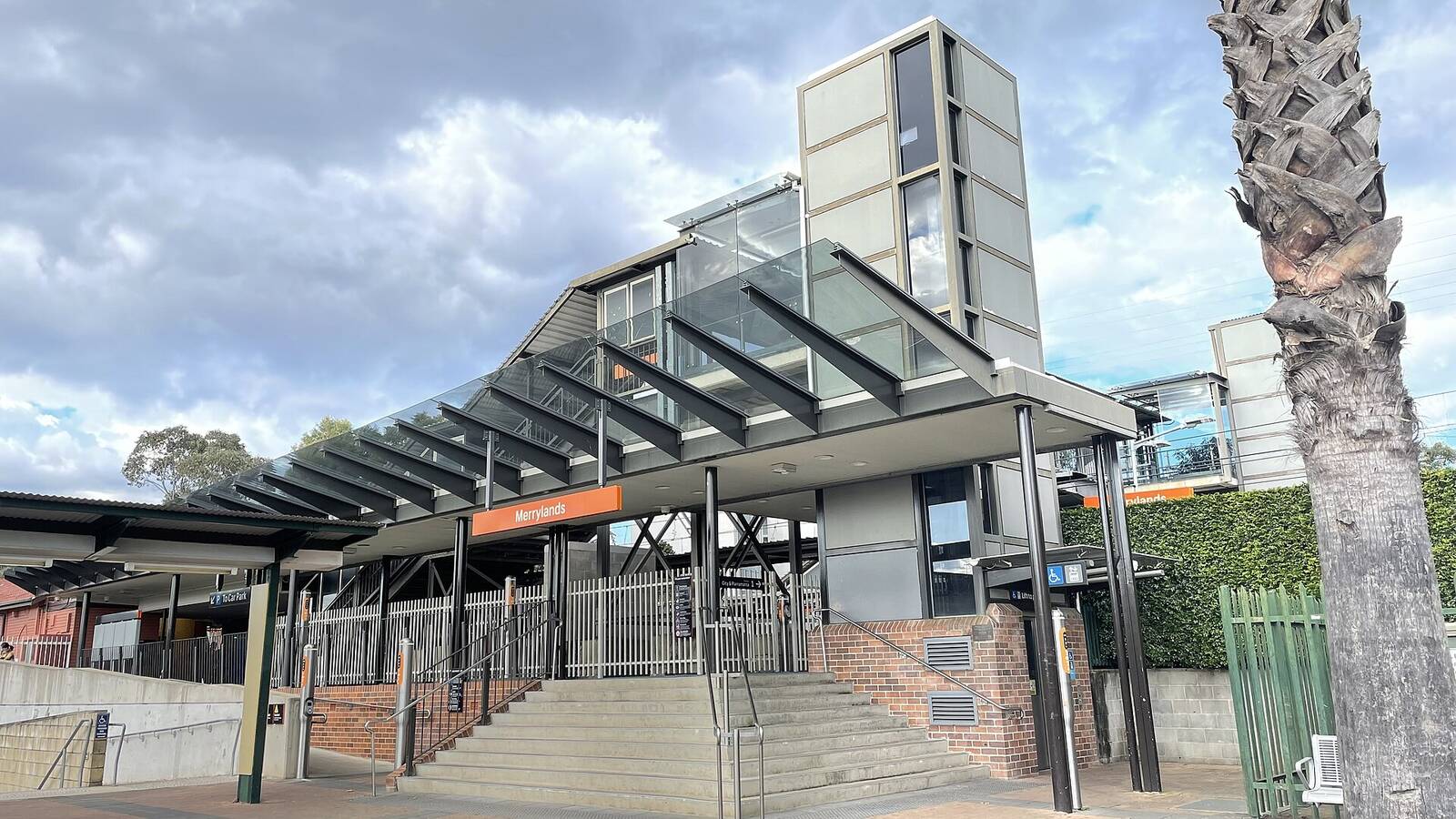 Steps, glass canopy and lift tower at the entrance to Merrylands railway station