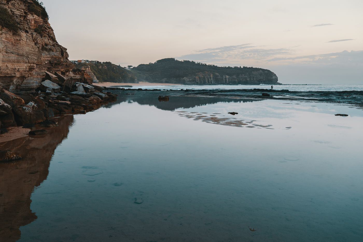 Still rock pool reflecting the sky at dawn on the Northern Beaches coast