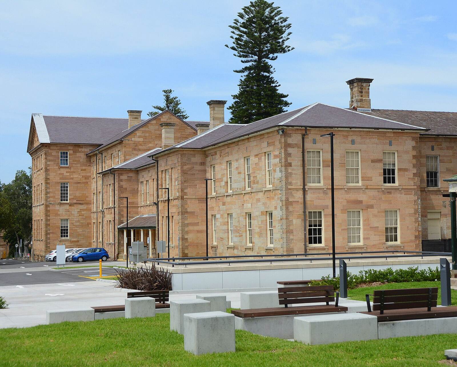 Sandstone heritage building with a tall Norfolk Island pine in the grounds of Prince of Wales Hospital, Randwick