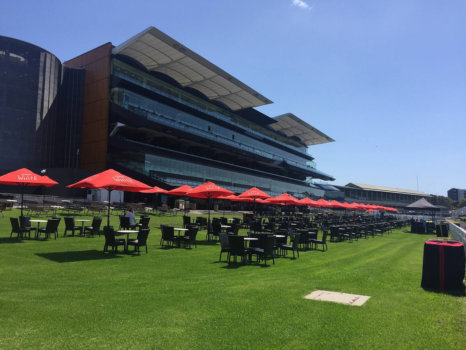 The Queen Elizabeth II Grandstand at Royal Randwick Racecourse with red umbrellas on the lawn