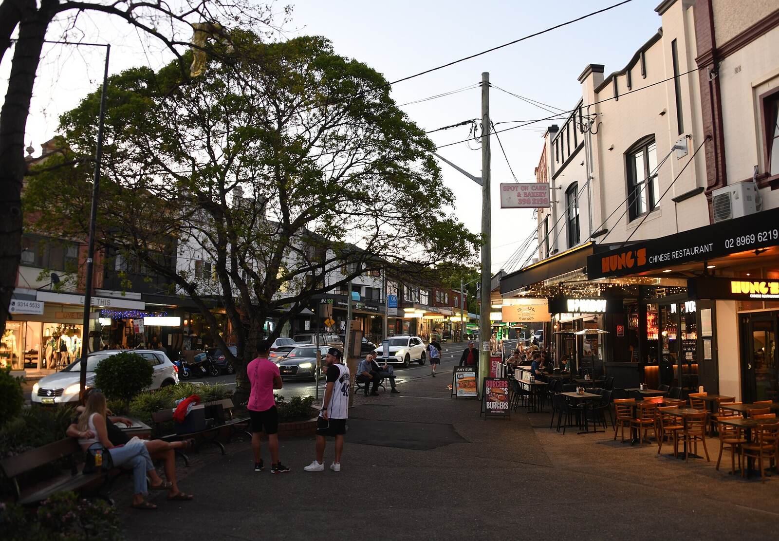 Outdoor tables, restaurants and a large shade tree at The Spot in Randwick in the early evening