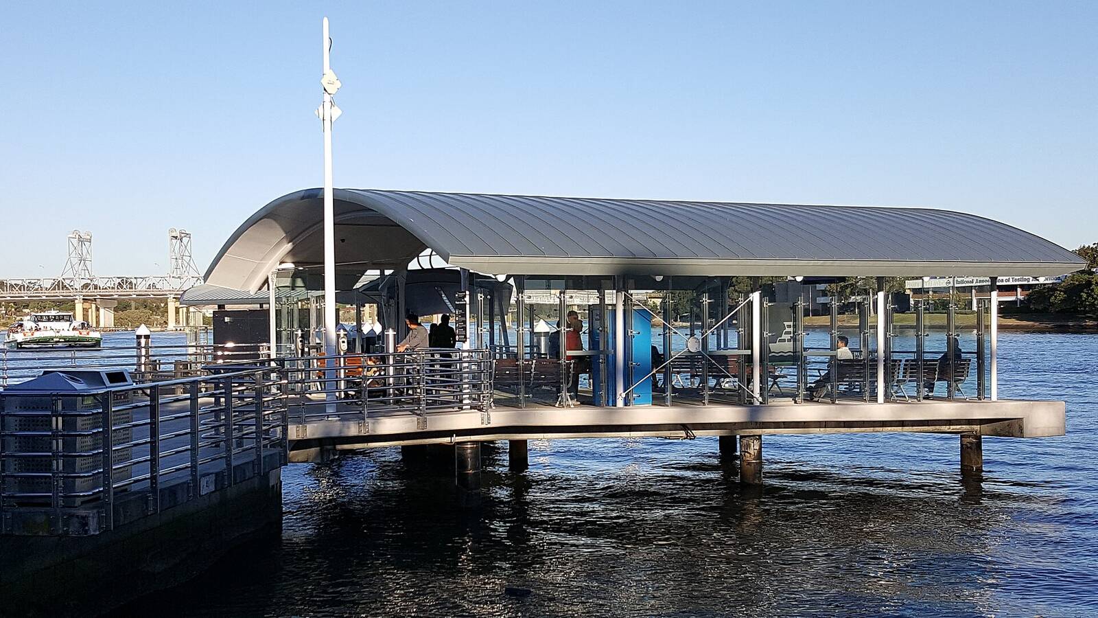 Meadowbank ferry wharf with its curved roof over the Parramatta River, Ryde Bridge in the distance