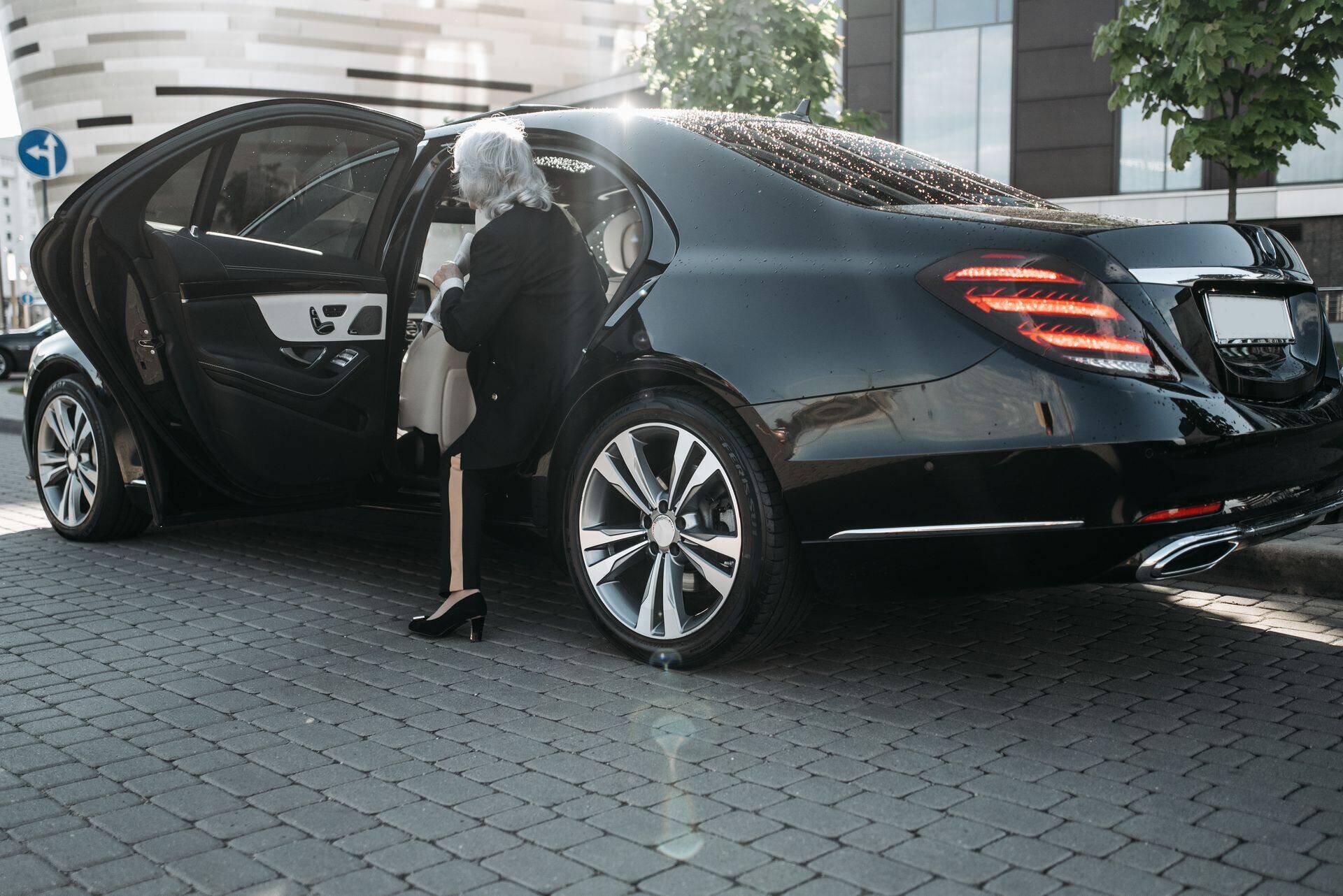 Older woman stepping into the back seat of a black sedan
