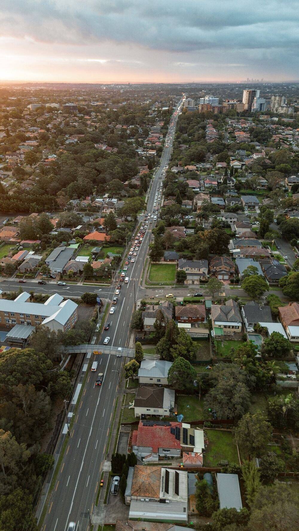 Aerial view straight down a long suburban main road lined with houses and trees