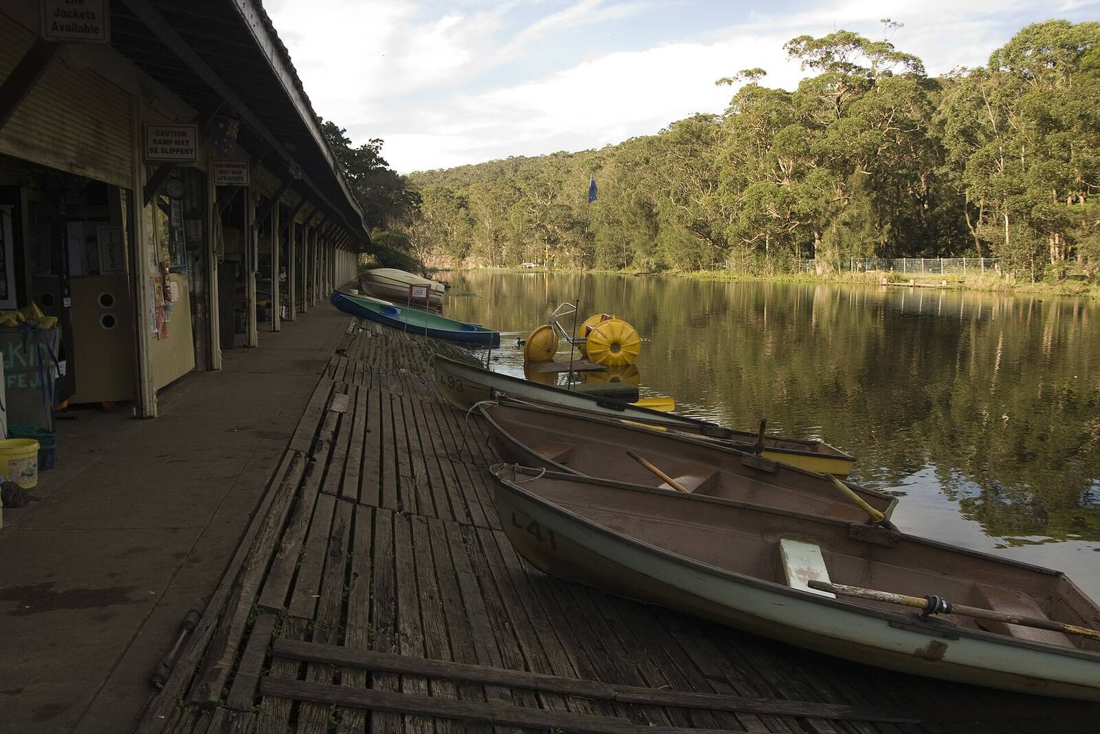 Rowboats tied up along the timber deck of the Audley Boatshed on the Hacking River
