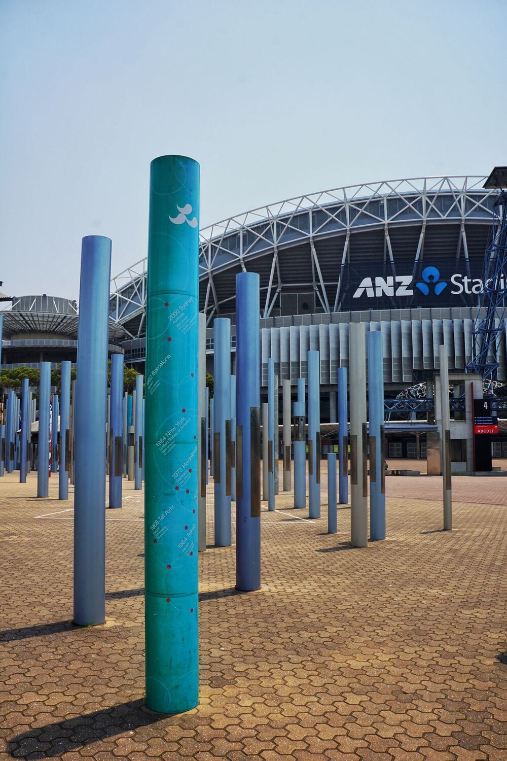 Stadium at Sydney Olympic Park behind a plaza of tall coloured poles