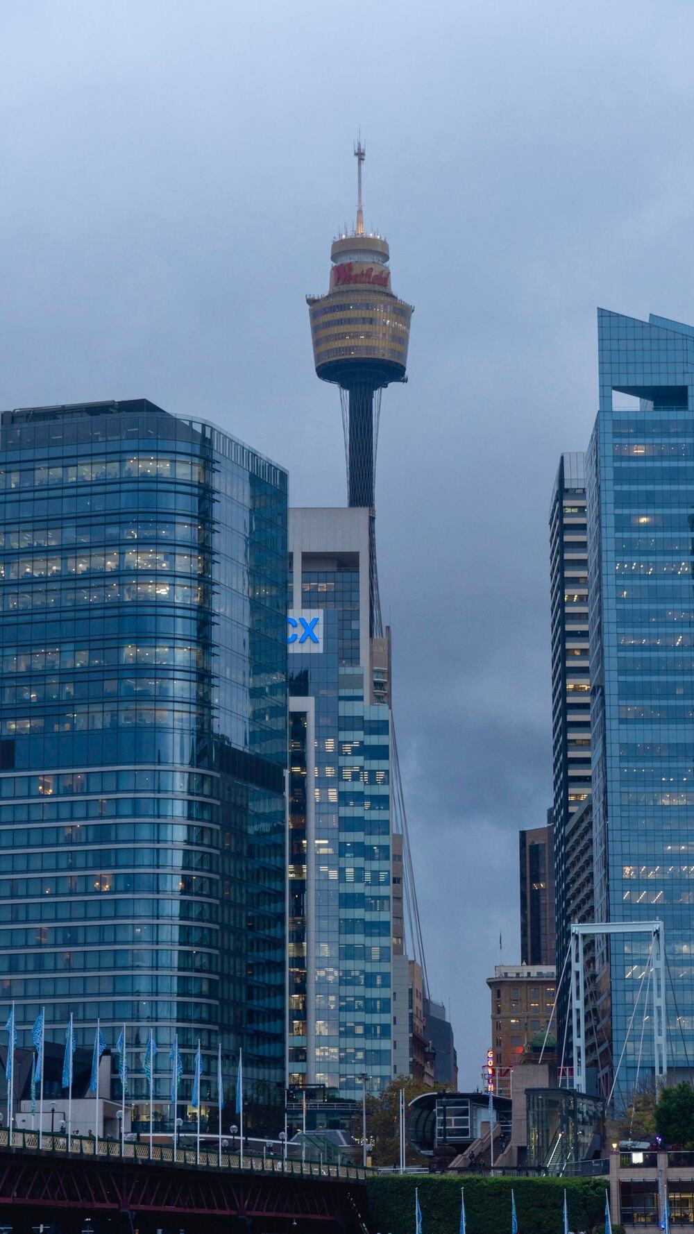 Sydney Tower rising between glass office buildings in the CBD