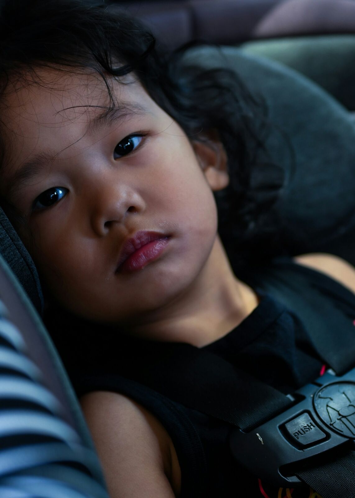 Toddler buckled into a harnessed child car seat with the chest clip done up